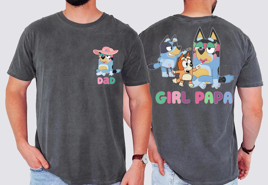 two different t-shirt designs featuring cartoon characters. The design on the left has a small cartoon character wearing a pink hat and the word "DAD" written below it. The design on the right has a larger cartoon character wearing a blue hat and the word "GIRL PAPA" written below it.