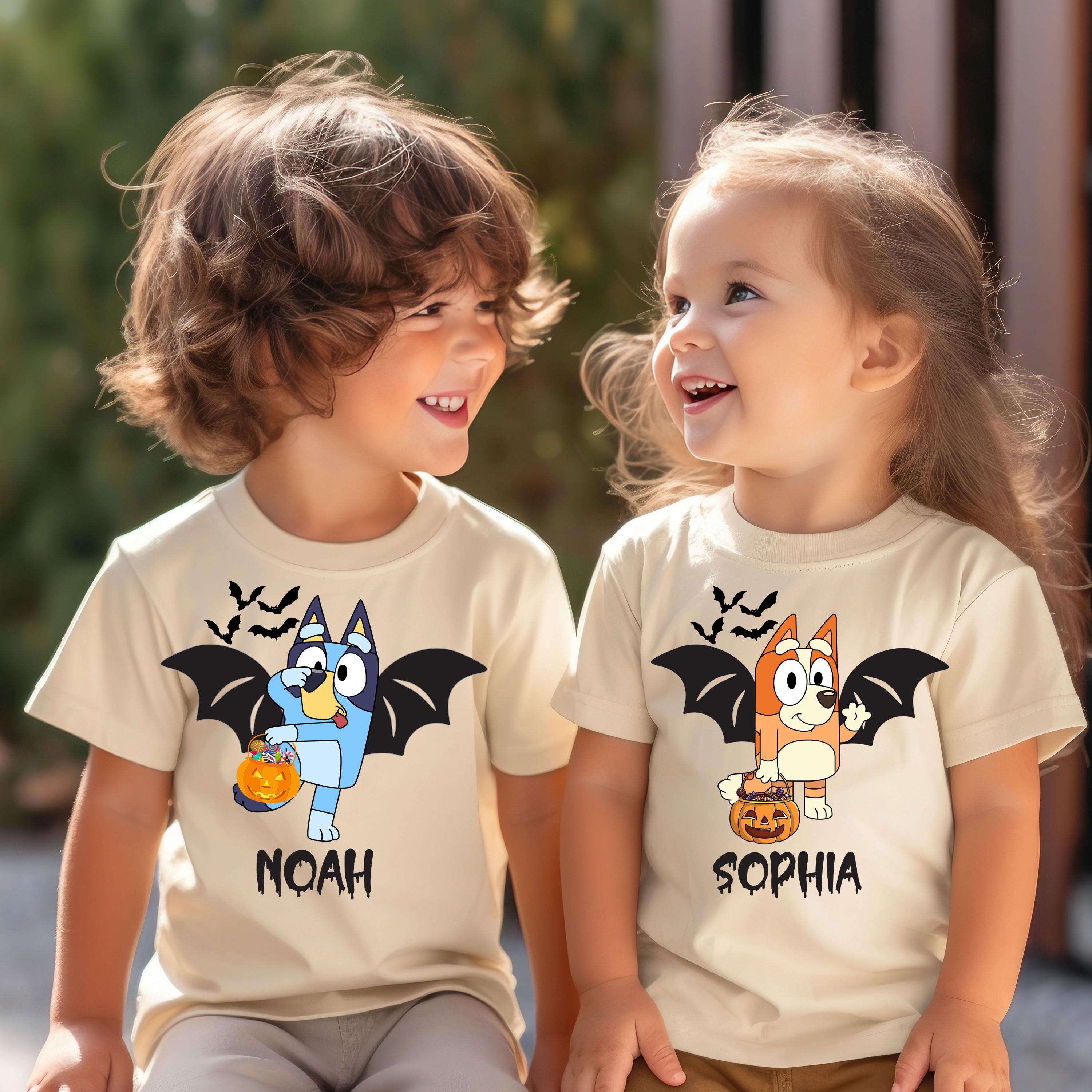 Two young children wearing t-shirts with cartoon images of a blue bat and a brown bat, along with the names Noah and Sophia printed on them.