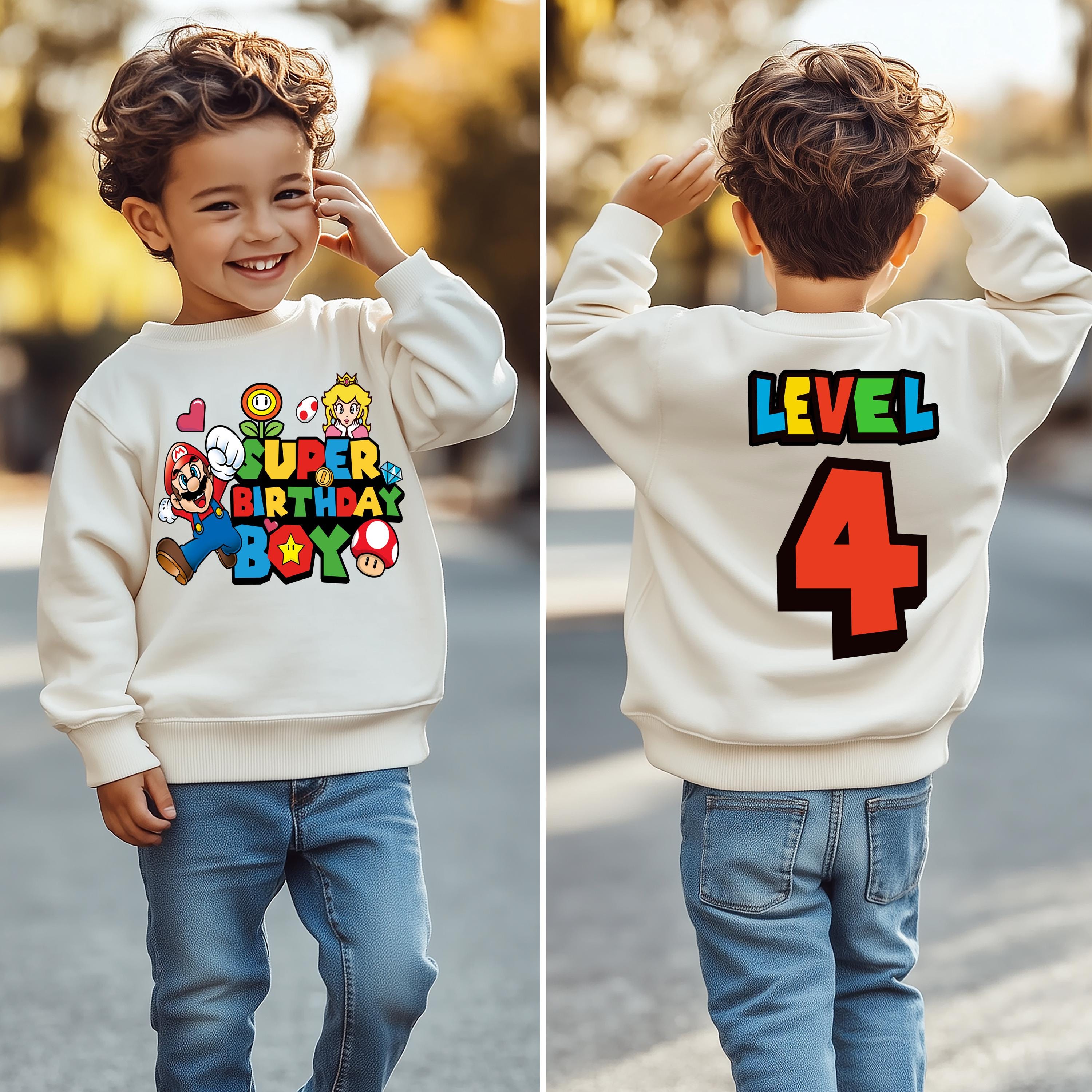 a young boy wearing a birthday sweatshirt and jeans