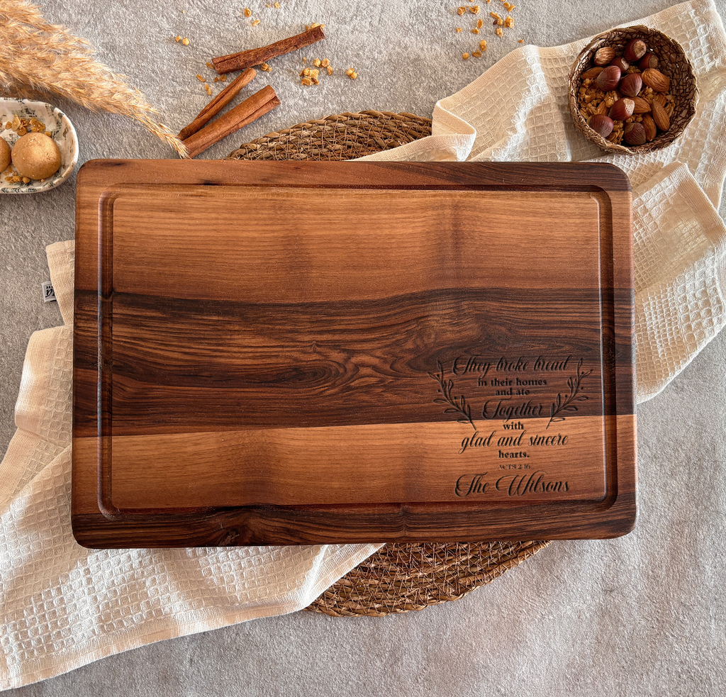 a wooden cutting board with a personalized message engraved on it, placed on a table with various food items and spices.