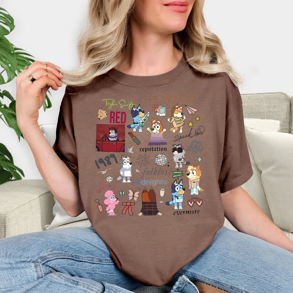 A woman wearing a brown t-shirt with various cartoon characters and text printed on it, sitting on a couch.