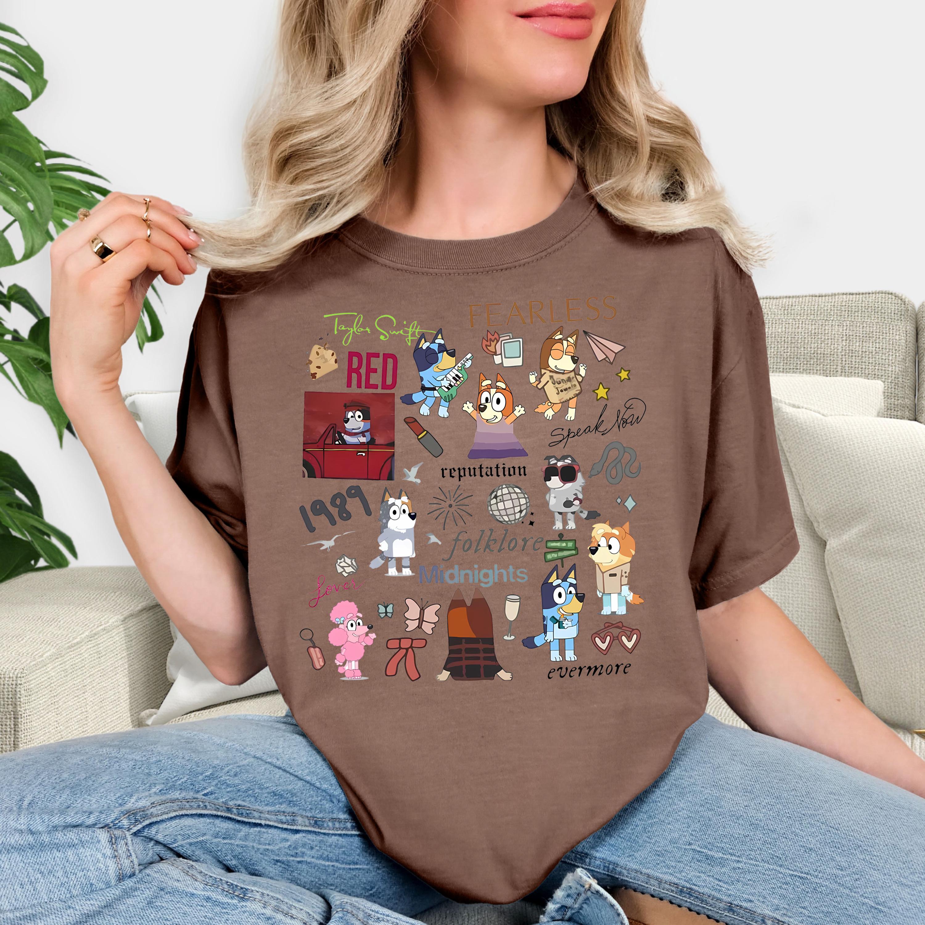 A woman wearing a brown t-shirt with various cartoon characters and text printed on it, sitting on a couch.