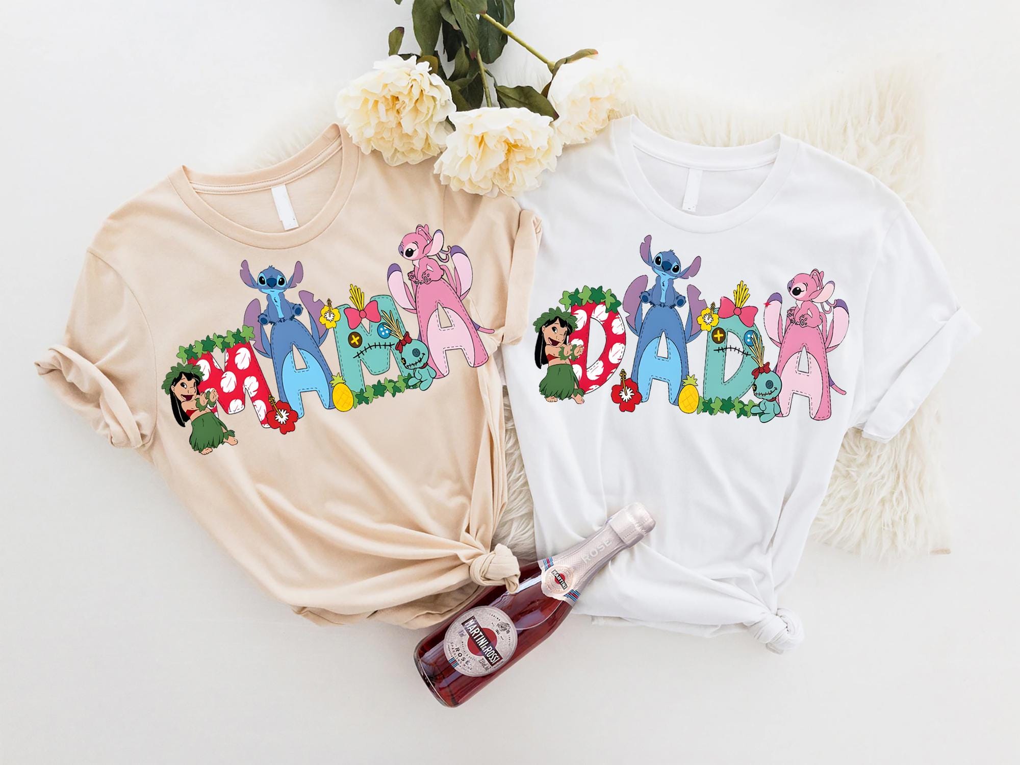 two t-shirts with colorful cartoon characters printed on them, along with a bottle of wine and some flowers.