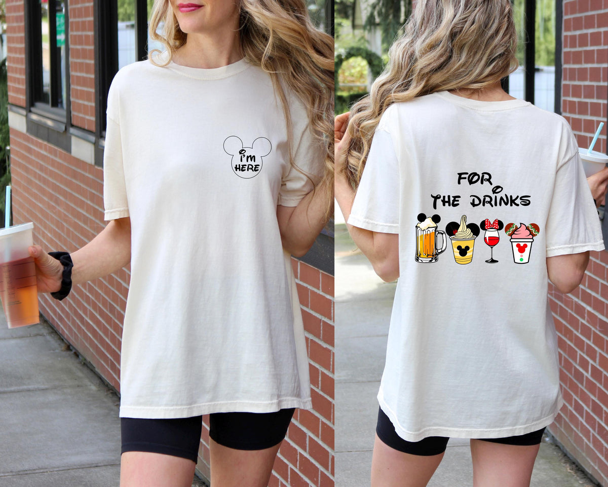 A woman wearing a white t-shirt with a playful design of Mickey Mouse and drinks, along with the text "I'm here for the drinks".