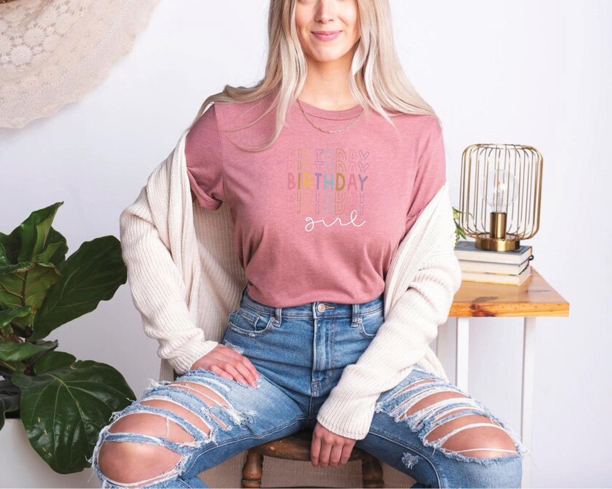 a woman sitting on a stool wearing ripped jeans
