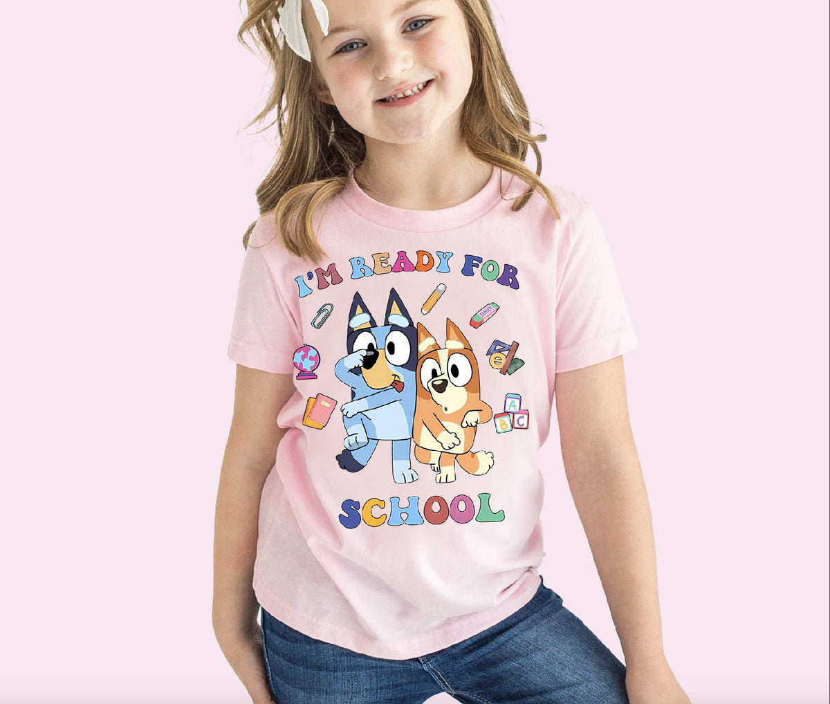 a young girl wearing a pink shirt with cartoon characters on it