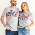 A man and a woman are standing next to each other, both wearing gray t-shirts with colorful cartoon characters printed on them.