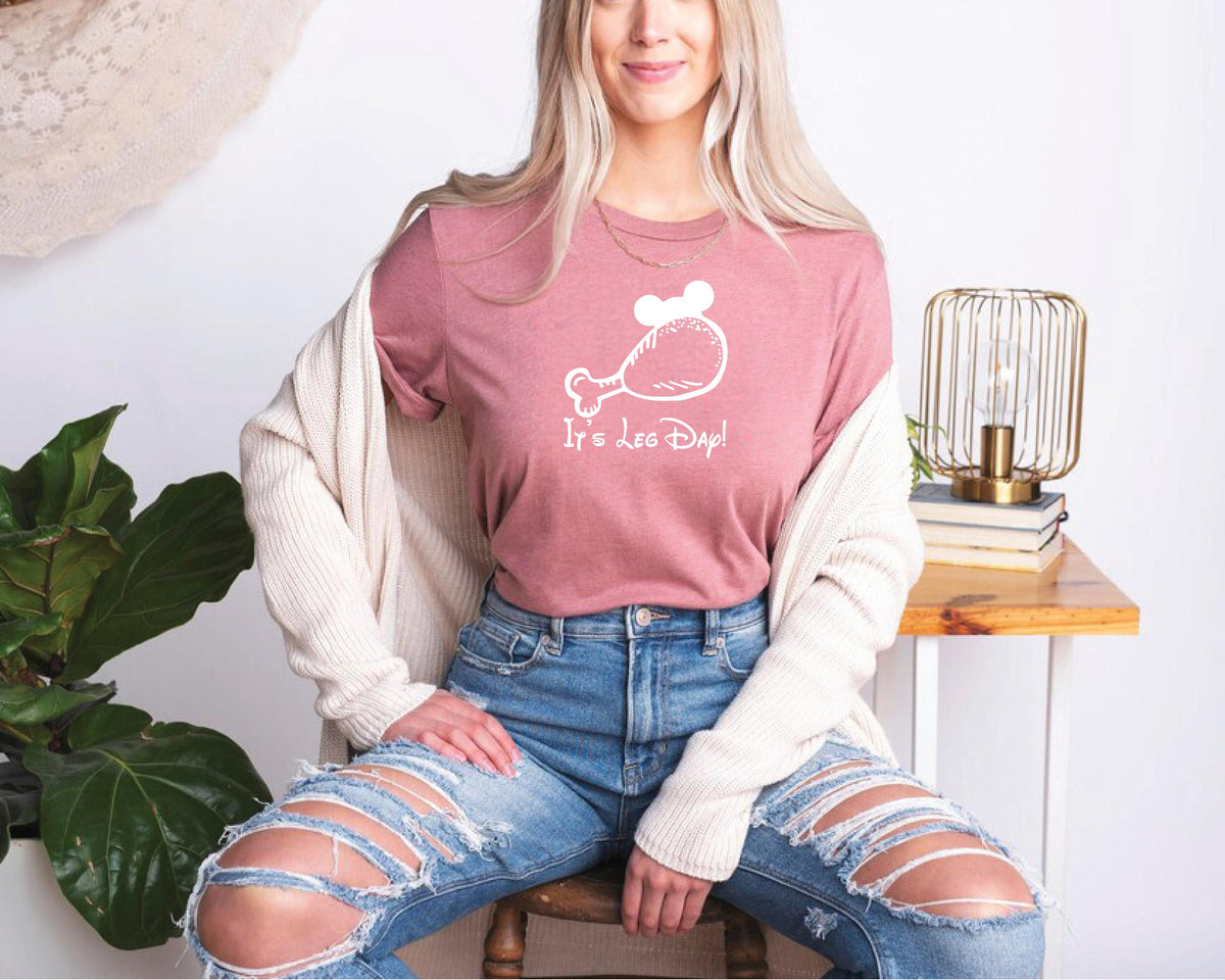a woman sitting on a chair wearing a pink shirt