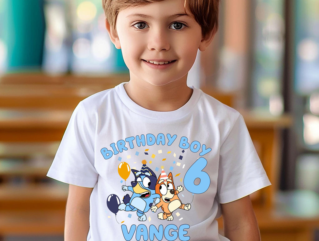 A young boy wearing a white t-shirt with a birthday theme and cartoon characters.