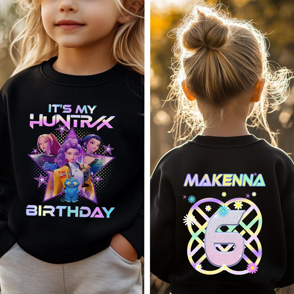 A young girl wearing a black shirt with a colorful graphic and text on it, celebrating her 6th birthday.