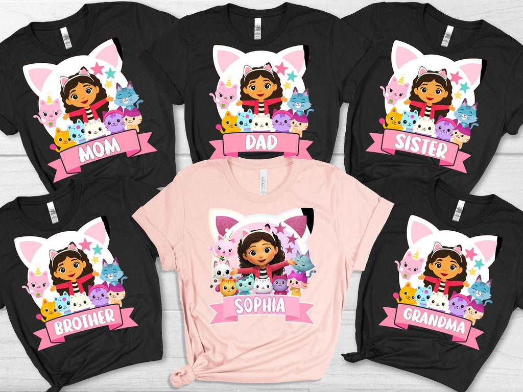 a collection of t-shirts featuring a character from the Dora the Explorer series, with the character's name and the names of family members or friends printed on them.