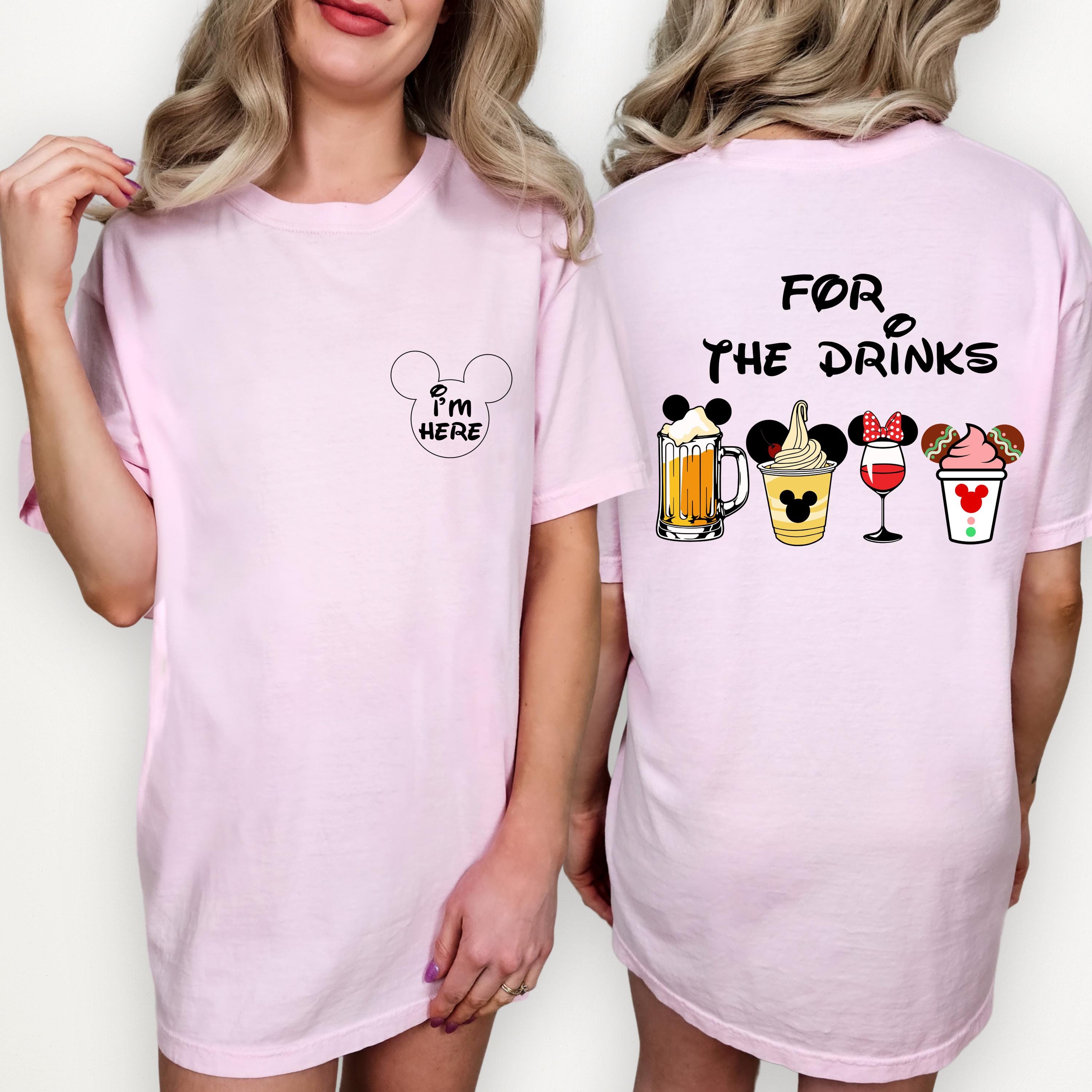A woman wearing a pink t-shirt with a playful design of various drinks and a Mickey Mouse logo.