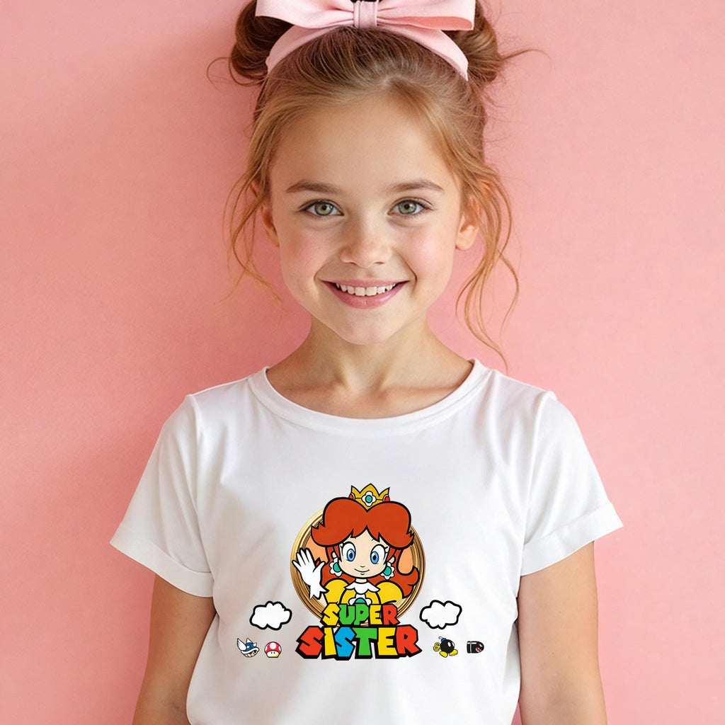 A young girl with a pink bow in her hair is smiling and wearing a white t-shirt with a colorful graphic of a character from the Super Mario video game series.