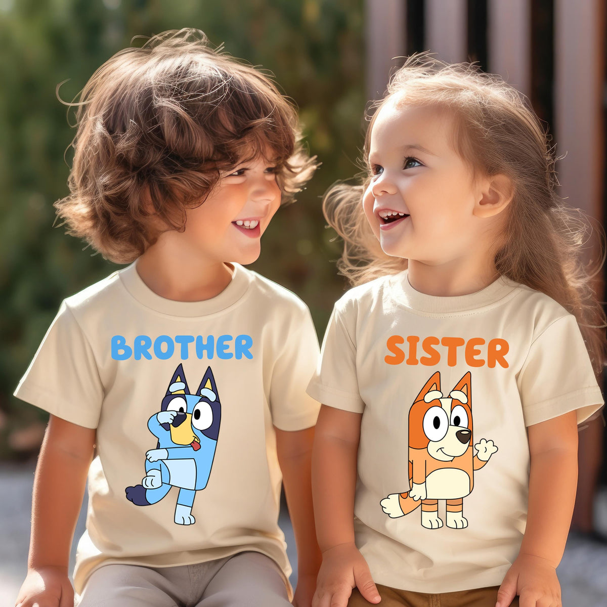 Two young children wearing matching t-shirts with cartoon characters on them, smiling and looking at each other.