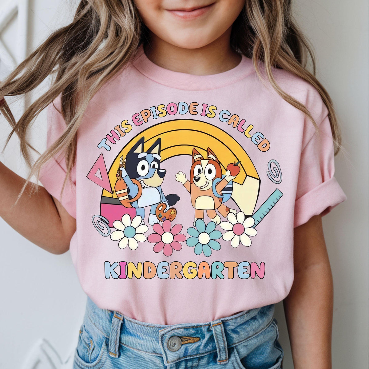 a little girl wearing a pink shirt with cartoon characters on it