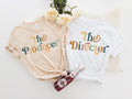 two t - shirts with the word the producer on them next to a bottle of