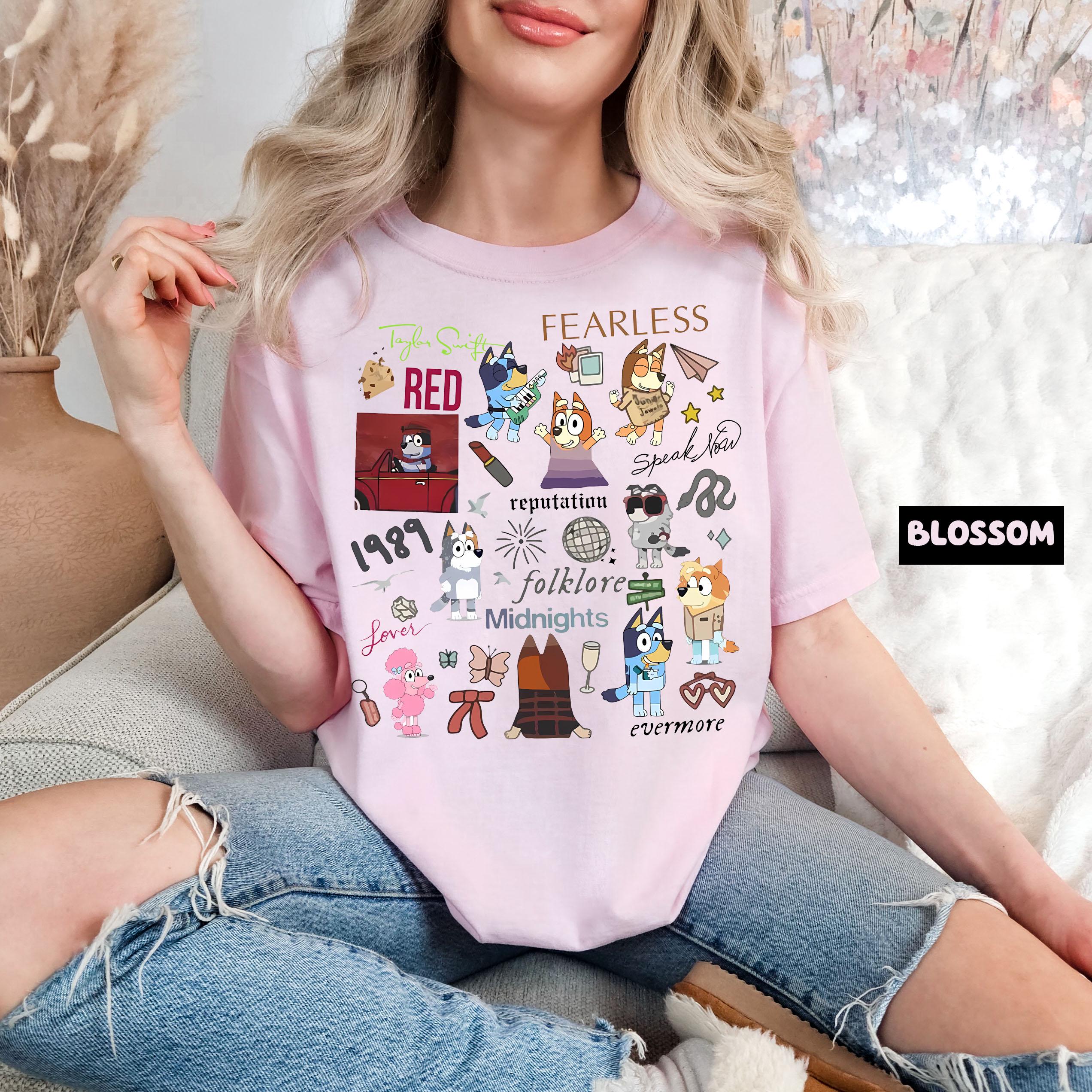 A woman wearing a pink t-shirt with various cartoon characters and text printed on it, sitting on a couch.