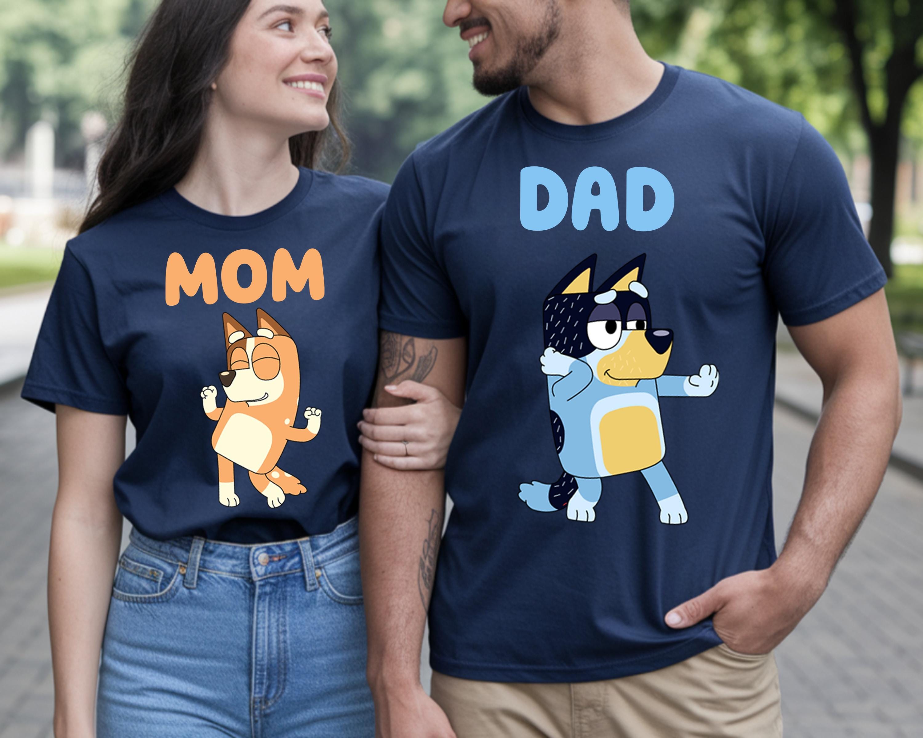 A man and a woman are standing together, both wearing blue t-shirts with cartoon characters on them.