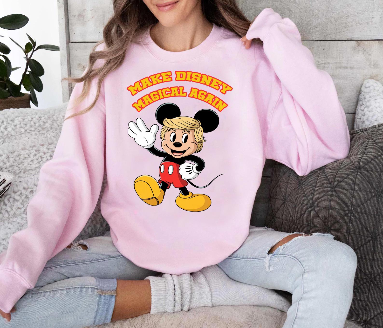 a woman sitting on a couch wearing a pink mickey mouse sweatshirt