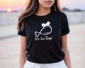 A woman wearing a black t-shirt with a white graphic and text printed on it.