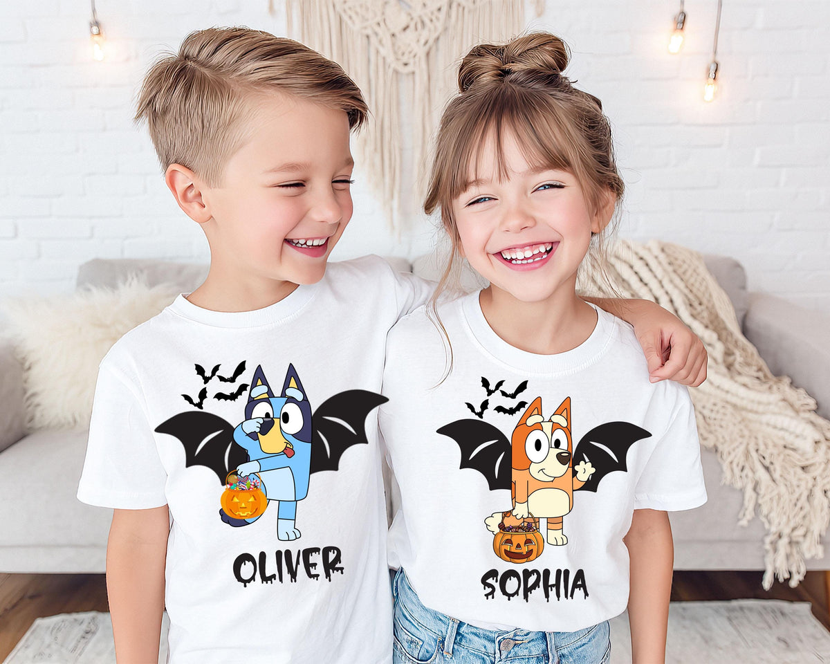 Two children wearing white t-shirts with cartoon bats and the names "Oliver" and "Sophia" printed on them, smiling and posing together.