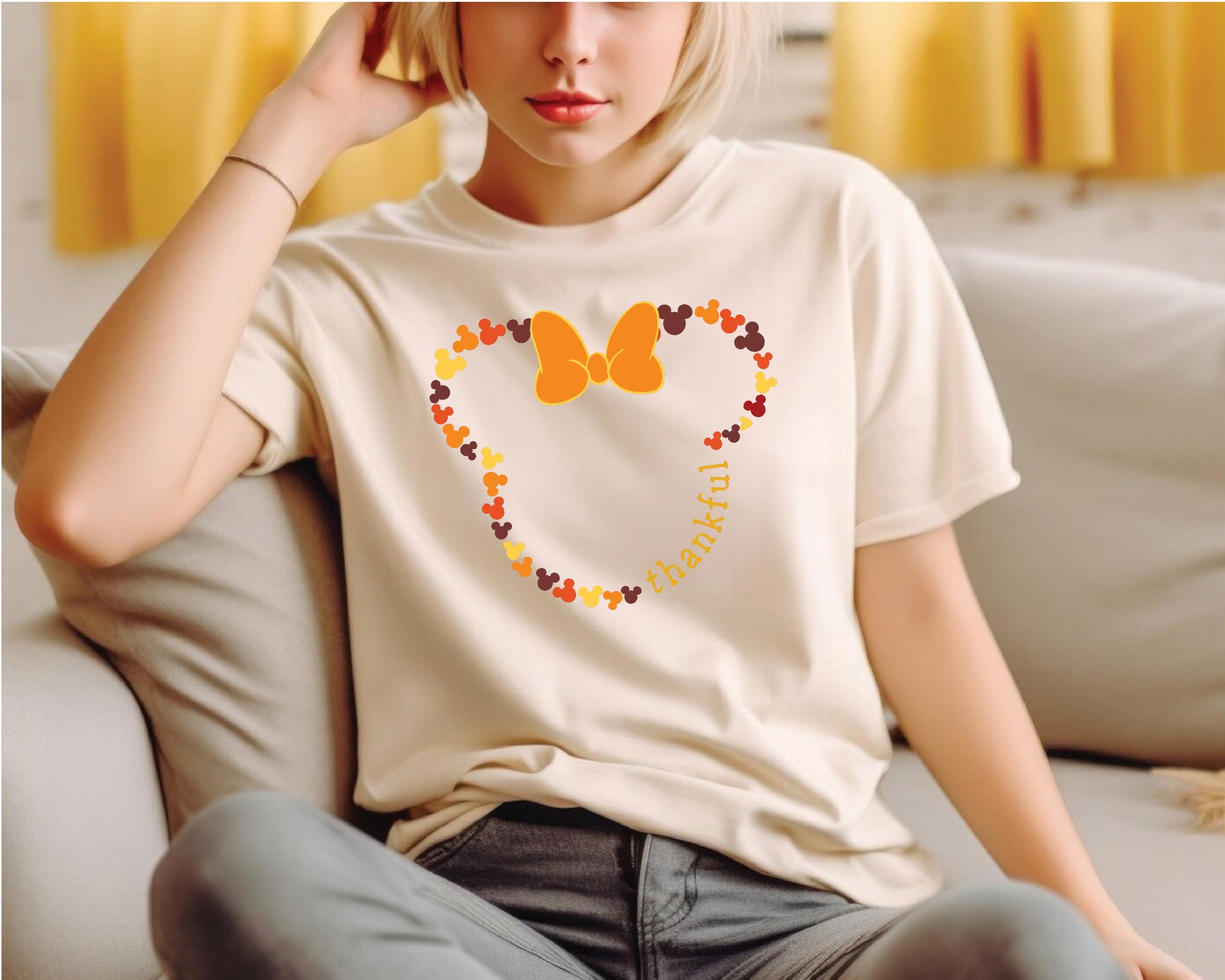 a woman sitting on a couch wearing a mickey mouse shirt