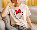 a woman sitting on a couch wearing a minnie mouse t - shirt